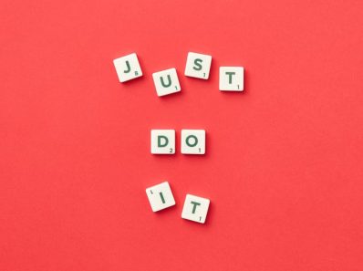 Motivational phrase 'Just Do It' spelled with Scrabble letters on a red background.